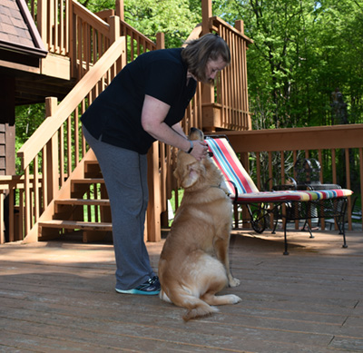 Amy Durfey training a dog on a wood deck.